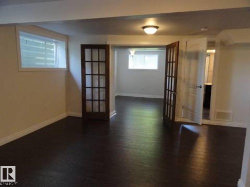 Expansive interior space featuring dark wood-finish flooring, white baseboards, and light-toned walls - 9815 68 Avenue, Edmonton, AB - Indoor Photo Showing Other Room