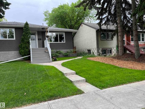 Gray stucco exterior with white-framed windows and a contrasting gray stone-look foundation - 9815 68 Avenue, Edmonton, AB - Outdoor