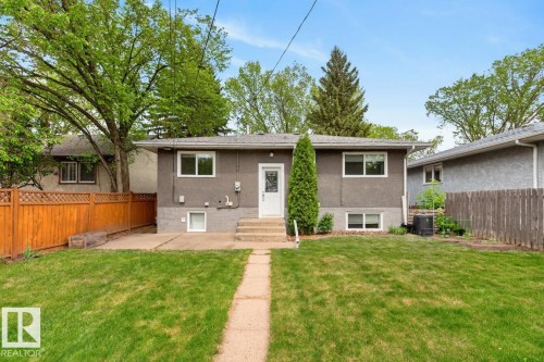Rear exterior featuring stucco finish, white trim windows, and a paved walkway - 9815 68 Avenue, Edmonton, AB - Outdoor