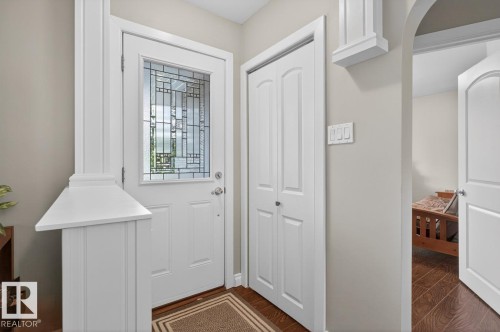 Entryway featuring a white door with decorative glass, wood-finish flooring, a bi-fold closet, and neutral wall tones - 9815 68 Avenue, Edmonton, AB - Indoor Photo Showing Other Room