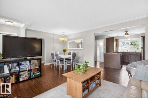 Open-concept living area featuring wood-finish flooring, crown molding, and a neutral wall palette - 9815 68 Avenue, Edmonton, AB - Indoor Photo Showing Living Room
