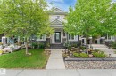 Two-story residential exterior featuring light-colored siding, a dark stone facade, and white trim accents - 5813 63 Street, Beaumont, AB 