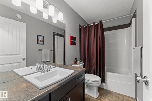 Bathroom featuring a single vanity with an integrated sink, chrome faucet, and a large wall-mounted mirror - 5813 63 Street, Beaumont, AB 