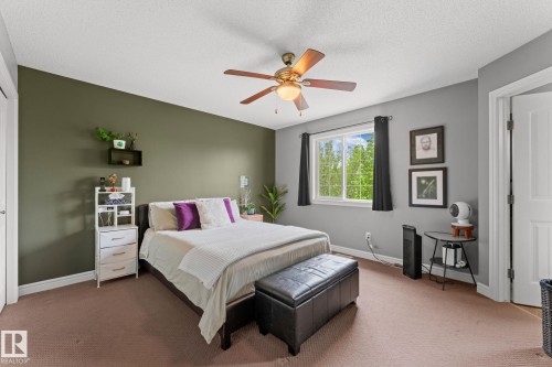 Comfortable bedroom with neutral carpeting and a ceiling fan light fixture - 5813 63 Street, Beaumont, AB 