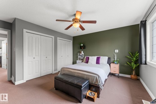 Bedroom featuring an accent wall, window with dark curtains, and light-colored carpet flooring - 5813 63 Street, Beaumont, AB 
