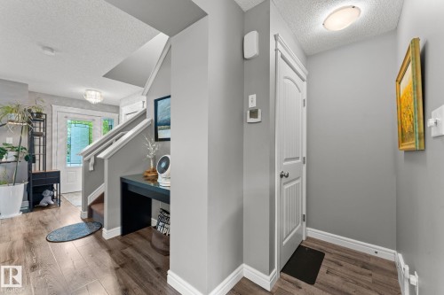 Entryway featuring wood-finish flooring, light grey walls, white trim, and a staircase with white railings - 5813 63 Street, Beaumont, AB 