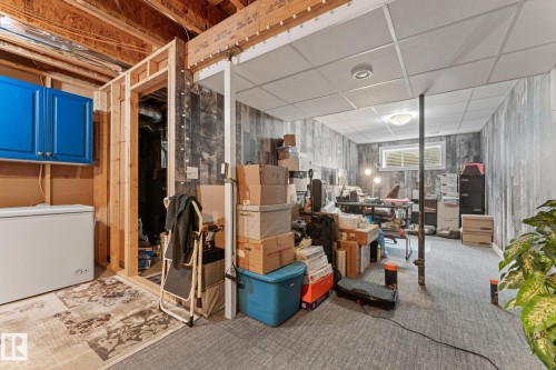 Basement featuring exposed ceiling joists, wood-look wall paneling, a drop ceiling, and a single horizontal window - 5813 63 Street, Beaumont, AB 