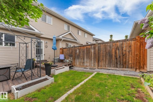 Private backyard featuring a wooden deck, manicured lawn, and a tall wood privacy fence - 5813 63 Street, Beaumont, AB 