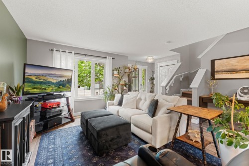 Living area featuring wood-finish flooring, a neutral color palette, multiple windows, and a staircase with white risers and handrails - 5813 63 Street, Beaumont, AB 