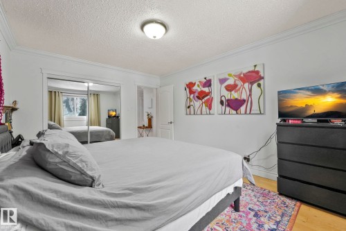 Light wood-finish flooring complements the crown molding and white walls - 303 10165 113 Street, Edmonton, AB - Indoor Photo Showing Bedroom