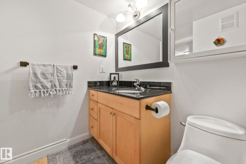 Bathroom featuring a light wood-finish vanity with ample storage, a black countertop, and an undermount sink - 303 10165 113 Street, Edmonton, AB - Indoor Photo Showing Bathroom