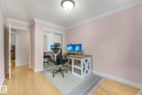 Light wood-finish flooring with white baseboards and crown molding - 303 10165 113 Street, Edmonton, AB - Indoor Photo Showing Office