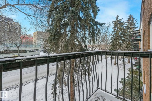 Balcony with black metal railings, offering urban and evergreen tree surroundings - 303 10165 113 Street, Edmonton, AB - Outdoor With Balcony
