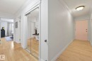 Hallway featuring light wood-finish flooring, mirrored sliding closet doors, crown molding, and baseboards - 303 10165 113 Street, Edmonton, AB  - Indoor Photo Showing Other Room 