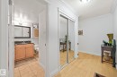 Hallway featuring wood-finish flooring, crown molding, and a mirrored closet - 303 10165 113 Street, Edmonton, AB  - Indoor 