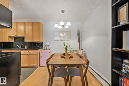 Dining area featuring a wood-finish table, pendant light fixture, and wood-finish flooring - 303 10165 113 Street, Edmonton, AB - Indoor