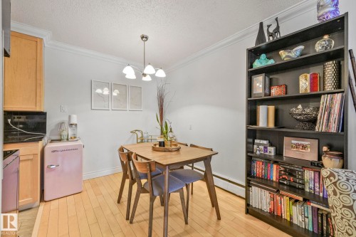 Dining area featuring wood-finish flooring, crown molding, and a four-light chandelier - 303 10165 113 Street, Edmonton, AB - Indoor
