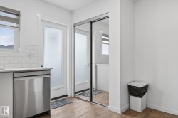 Kitchen area featuring a stainless steel dishwasher, white subway tile backsplash, and a white countertop - 