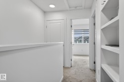 Upper-level hallway featuring a built-in shelving unit, recessed lighting, and carpeted flooring - 