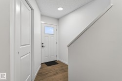 Entryway featuring a white paneled door with a transom window, wood-finish flooring, a recessed ceiling light, and a white interior door - 