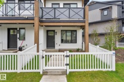 Contemporary townhouse exterior featuring white siding, dark trim windows, and a dark entry door - 