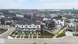 Contemporary multi-level townhome featuring a dark shingle roof, white siding, and black window frames - 