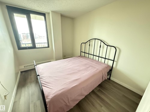 Room featuring large windows with dark frames, light wood-finish flooring, white baseboards, and neutral wall paint - 706 10125 109 Street, Edmonton, AB 
