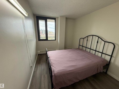 Room featuring wood-finish flooring, a window with dark framing, and a white baseboard heater - 706 10125 109 Street, Edmonton, AB 