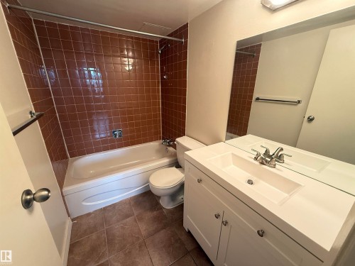 Bathroom featuring a white vanity with integrated sink, chrome faucet, and a large wall-mounted mirror - 706 10125 109 Street, Edmonton, AB 