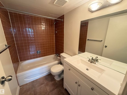 Bathroom featuring a white vanity with integrated sink, chrome faucet, and a large wall-mounted mirror - 706 10125 109 Street, Edmonton, AB 