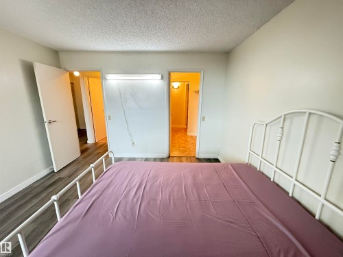 Bedroom featuring wood-finish flooring, light neutral wall paint, and a textured ceiling - 706 10125 109 Street, Edmonton, AB 