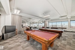 Expansive entertainment area featuring two pool tables, patterned carpet flooring, and abundant natural light from numerous windows - 