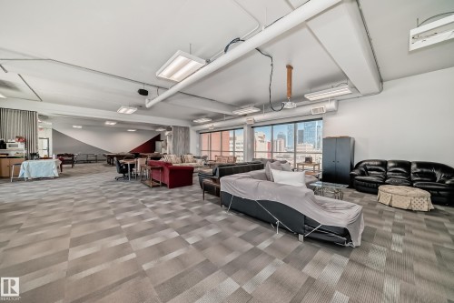Spacious open-concept room featuring patterned carpet flooring and expansive windows - 706 10125 109 Street, Edmonton, AB 