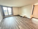 Spacious living area featuring wood-finish flooring, a large glass door to a balcony, and abundant natural light - 706 10125 109 Street, Edmonton, AB 