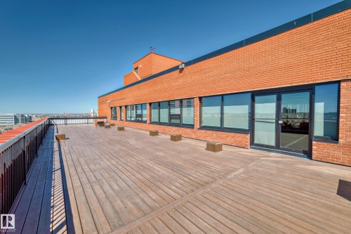Expansive rooftop terrace featuring wood-finish decking and a dark metal railing - 706 10125 109 Street, Edmonton, AB 