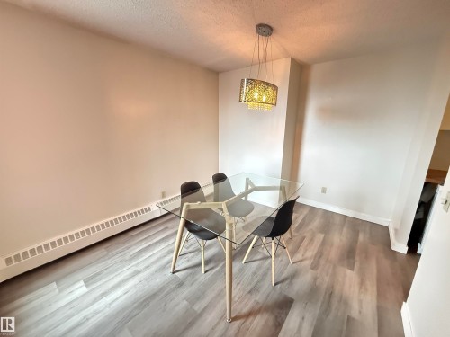 Dining area featuring wood-finish flooring, a contemporary chandelier, and neutral wall tones - 706 10125 109 Street, Edmonton, AB 