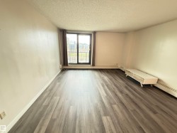 Spacious room featuring wood-finish flooring, a large window with vertical blinds, and a built-in wall heater - 