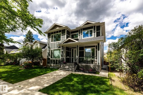 Contemporary two-story residence featuring dark siding with white trim accents, a prominent covered front porch with black railings, and a concrete walkway leading to the entrance - 10936 71 Avenue, Edmonton, AB 