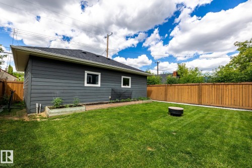 Expansive green lawn with a dark gray exterior structure featuring white-trimmed windows and a dark shingle roof - 10936 71 Avenue, Edmonton, AB 