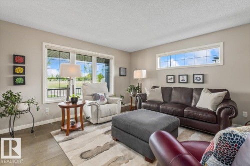 Living room featuring large picture windows, wood-finish flooring, a transom window, and neutral wall tones - 1086 Grantham Drive, Edmonton, AB 