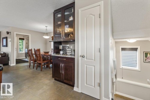Kitchenette area featuring dark wood-finish cabinetry, a granite-finish countertop, and glass-front upper cabinets - 1086 Grantham Drive, Edmonton, AB 