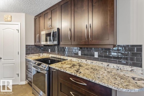 Modern kitchen featuring dark wood cabinetry with stainless steel hardware, a built-in microwave, and a stainless steel range - 1086 Grantham Drive, Edmonton, AB 