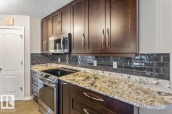 Modern kitchen featuring dark wood cabinetry with stainless steel hardware, a built-in microwave, and a stainless steel range - 