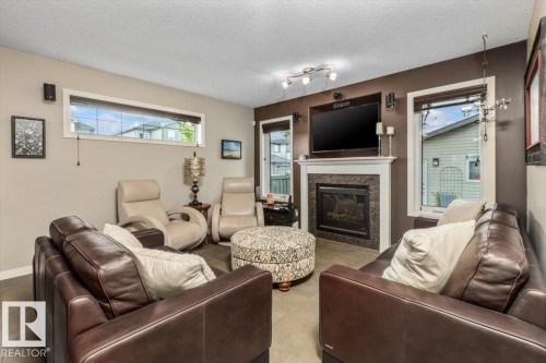 Living area featuring a gas fireplace with a white mantel and dark tile surround, track lighting, and tile flooring - 1086 Grantham Drive, Edmonton, AB 