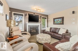Living area featuring a fireplace with a white mantel and dark stone surround, large windows with blinds, and tile flooring - 