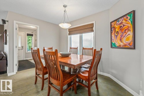 Dining area featuring tile flooring, a wood-finish dining table, and a contemporary pendant light fixture - 1086 Grantham Drive, Edmonton, AB 