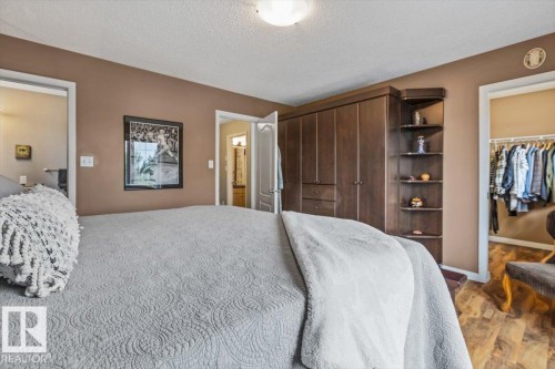 Bedroom featuring a built-in wardrobe with dark wood-finish cabinetry, integrated corner shelving, and light brown wall paint - 1086 Grantham Drive, Edmonton, AB 