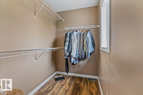 Walk-in closet featuring wood-finish flooring, neutral wall paint, white trim, and a window for natural light - 1086 Grantham Drive, Edmonton, AB 