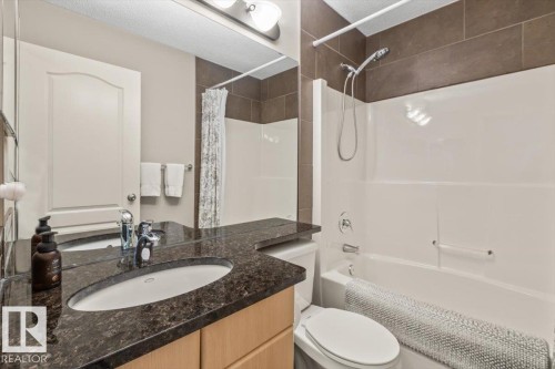 Bathroom featuring a vanity with an undermount sink, dark speckled countertop, wood-finish cabinetry, and chrome fixtures - 1086 Grantham Drive, Edmonton, AB 