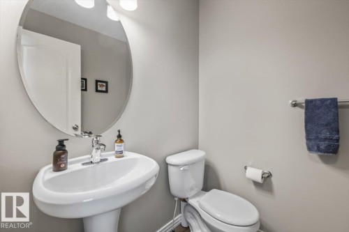 Pedestal sink with chrome faucet, oval mirror, and overhead vanity lighting - 1086 Grantham Drive, Edmonton, AB 